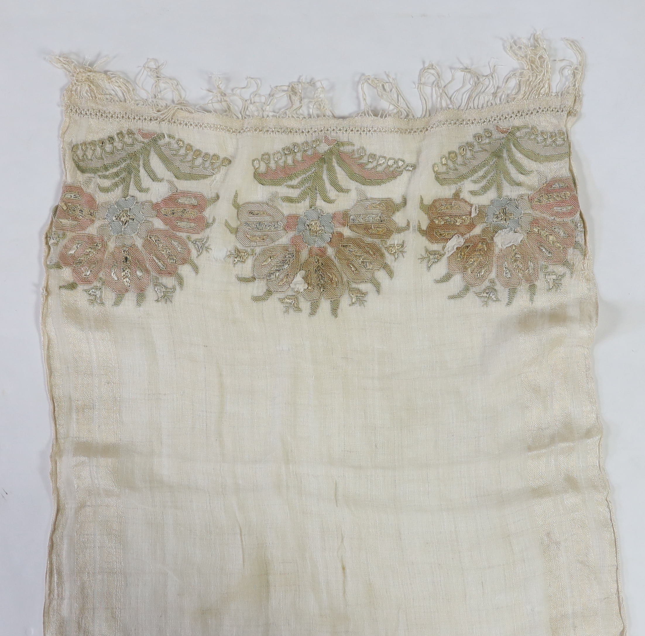 A 19th century Turkish towel, embroidered with flower motifs, in pastel shades, with fine silk fringing embroidered onto a fine hand spun linen, woven with stripes to each side, 48cm wide, 120cm long